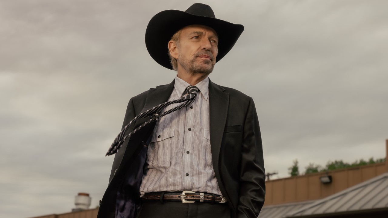 Billy Bob Thornton wearing a cowboy hat walking with his tie blowing in the wind. 