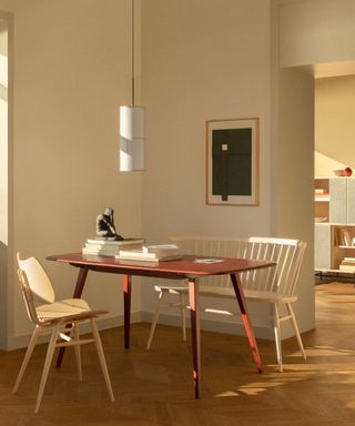 Red dining table with wooden chairs and white bed in a Scandinavian style dining room