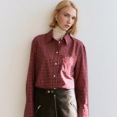 model wears red and thite plaid shirt layered over a white turtleneck and faux leather a-line skirt