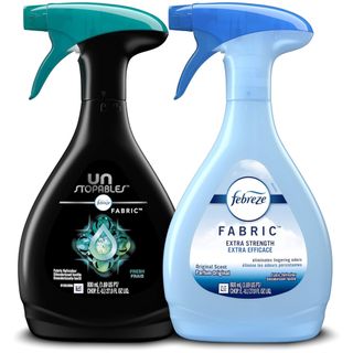 A blue spray bottle of Febreze fabric freshener next to a black and teal spray bottle