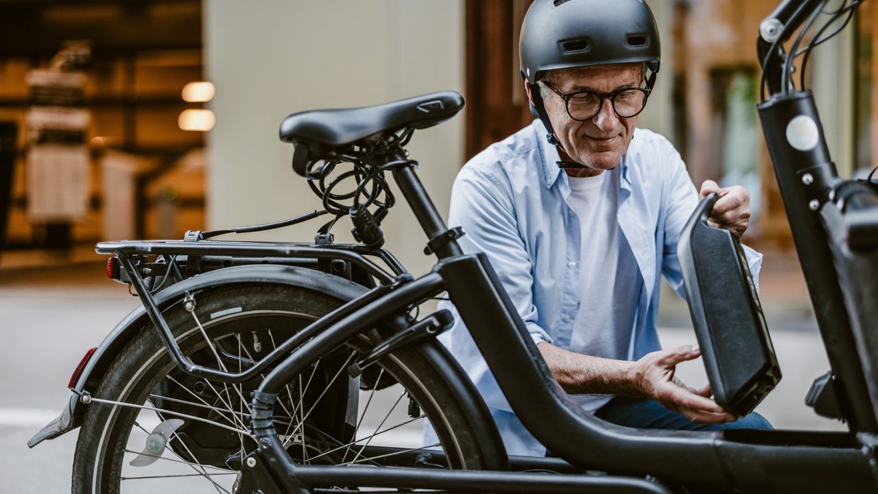 A man places an e-bike battery on his electric bike