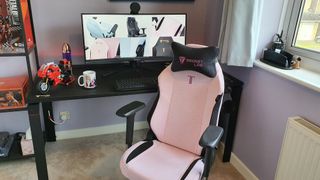 The Secretlab Titan XXS gaming chair in pink upholstery pictured in front of a gaming desk