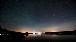 a bright meteorite streaks over a lake