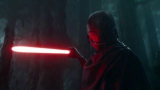 A masked villain is pointing a red lightsaber in a threatening manner.
