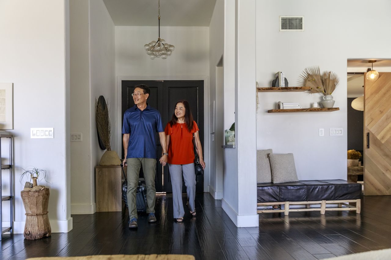 Smiling man and woman holding hands while arriving at vacation rental.