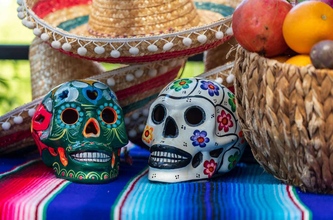 Two Mexican skulls, sombrero hat and basket of fruit