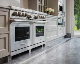 modern kitchen with double oven with neutral counters, a sleek floor, and a door out to the garden