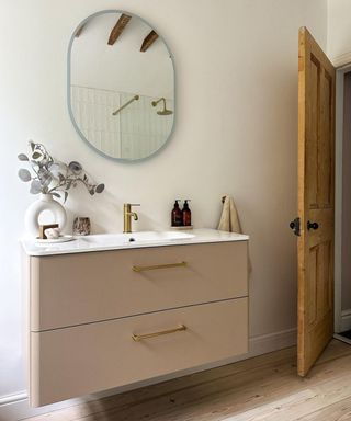 Bathroom sink with beige drawers and a round mirror