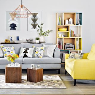 A white living room with a grey sofa and an yellow sofa arrange at 90 degrees to one another.