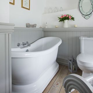 bathroom with grey panel and white wall bathtub flower pot and wooden floor