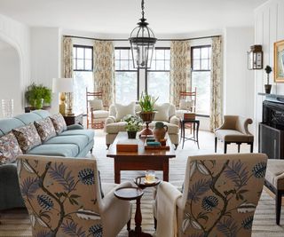 living room with white walls patterned armchairs and blue sofas and bay windows