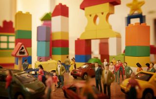 Toy cars and figurines in pretend plastic block town