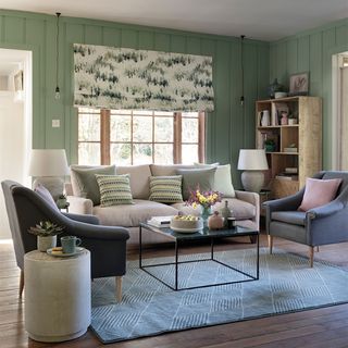 Small living room in green panelled room with sofa and two chairs