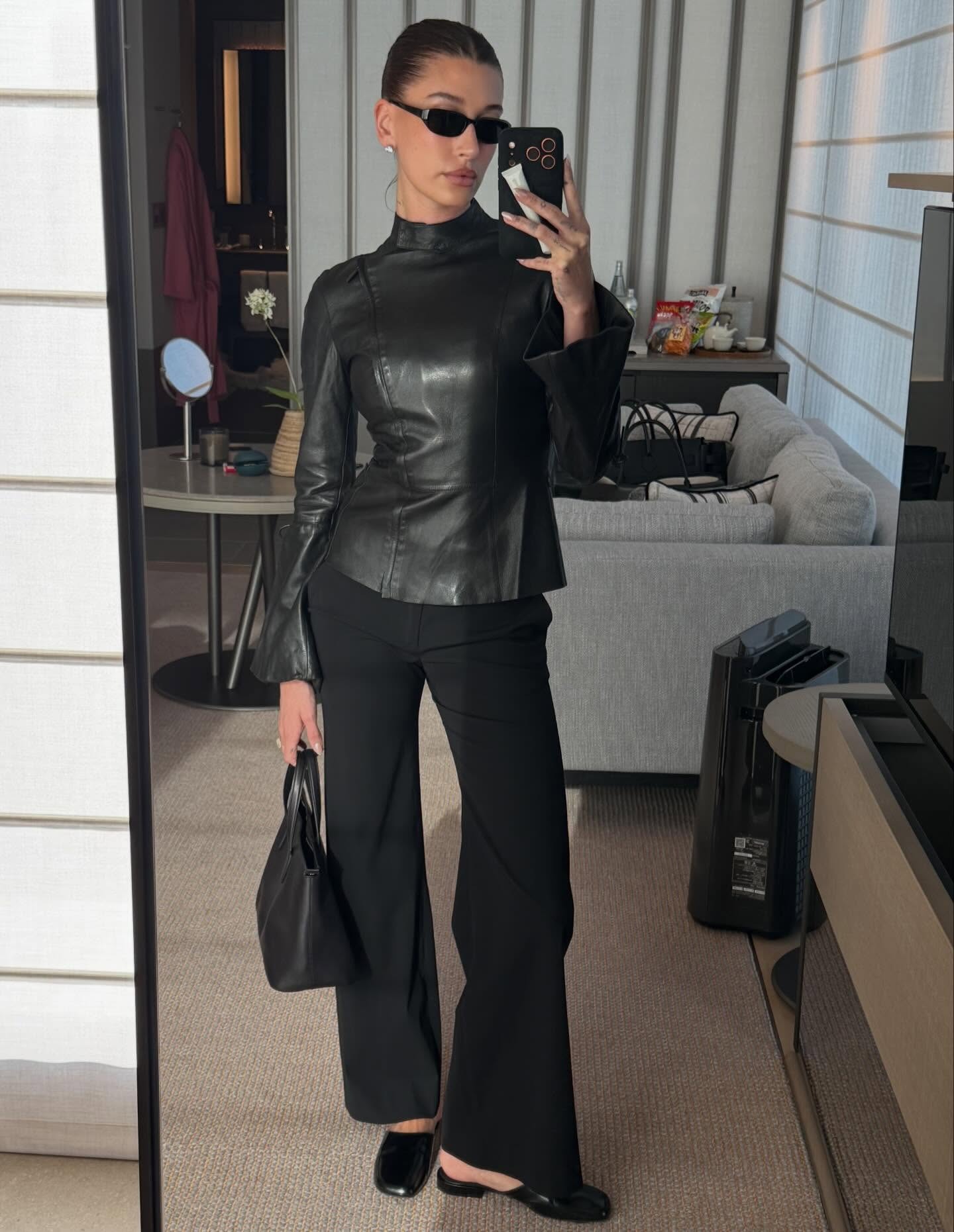 Hailey Bieber weras a leather jacket, black pants, and Penelope Mules.