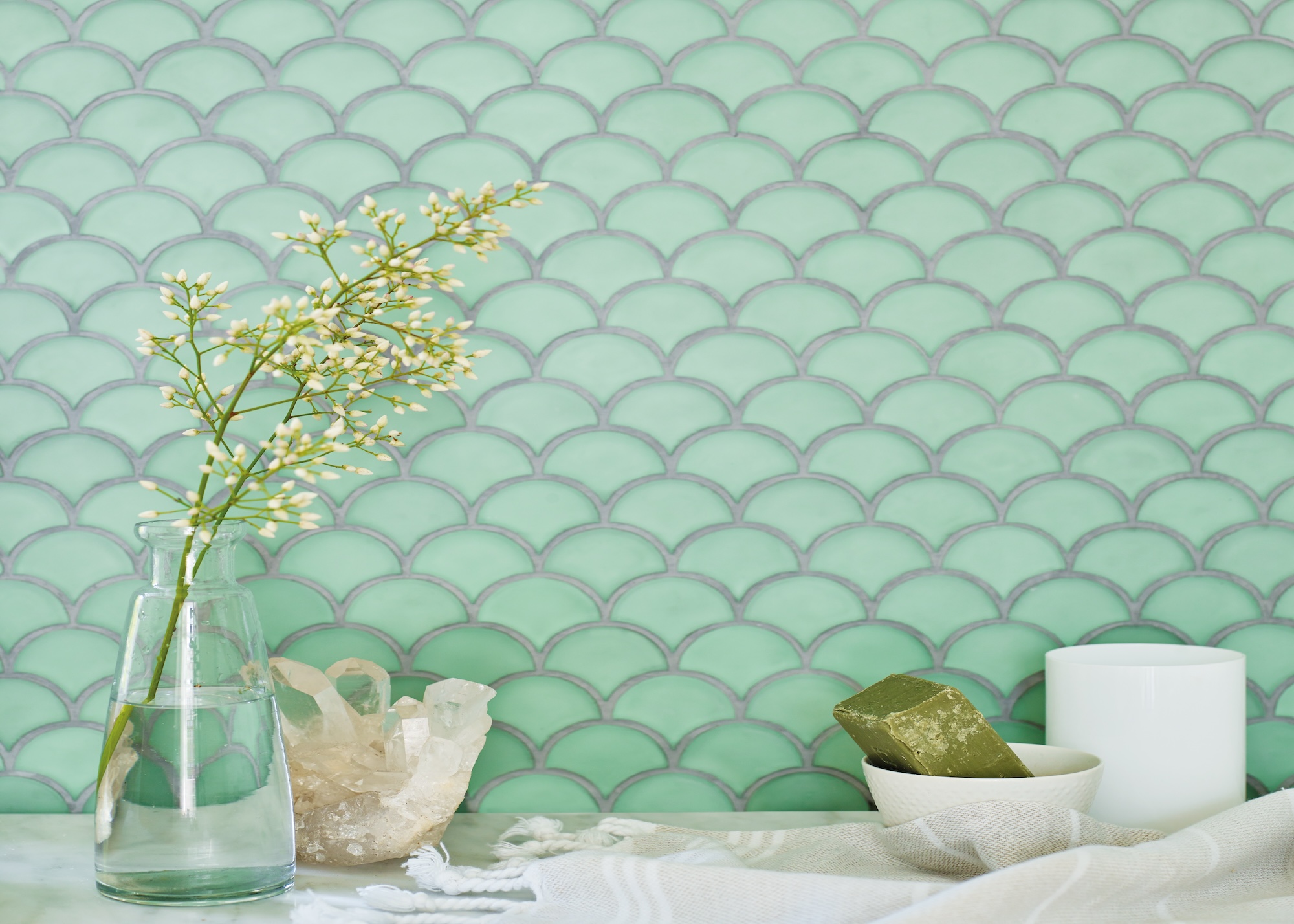 Glass wall tiles in a bathroom with a vase and a flower inside it