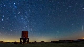 Meteors streak through the star-studded sky above a large water tanker in the desert.
