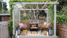 Stylish gray pergoda idea with hanging lanterns, and informal lounge area with rattan chairs and coffee table.