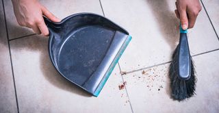 dustpan and brush used to sweep up mess as step for how to clean tile floor