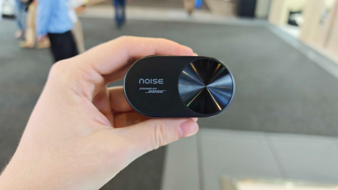 Noise Master Buds Open, held in a hand in a big expo center