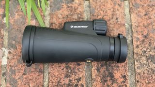 Celestron Outland X 10x50 monocular lying on brickwork