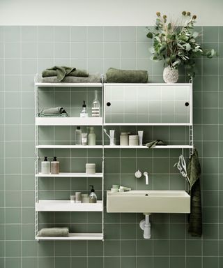 green tiled bathroom with modular storage system around the sink