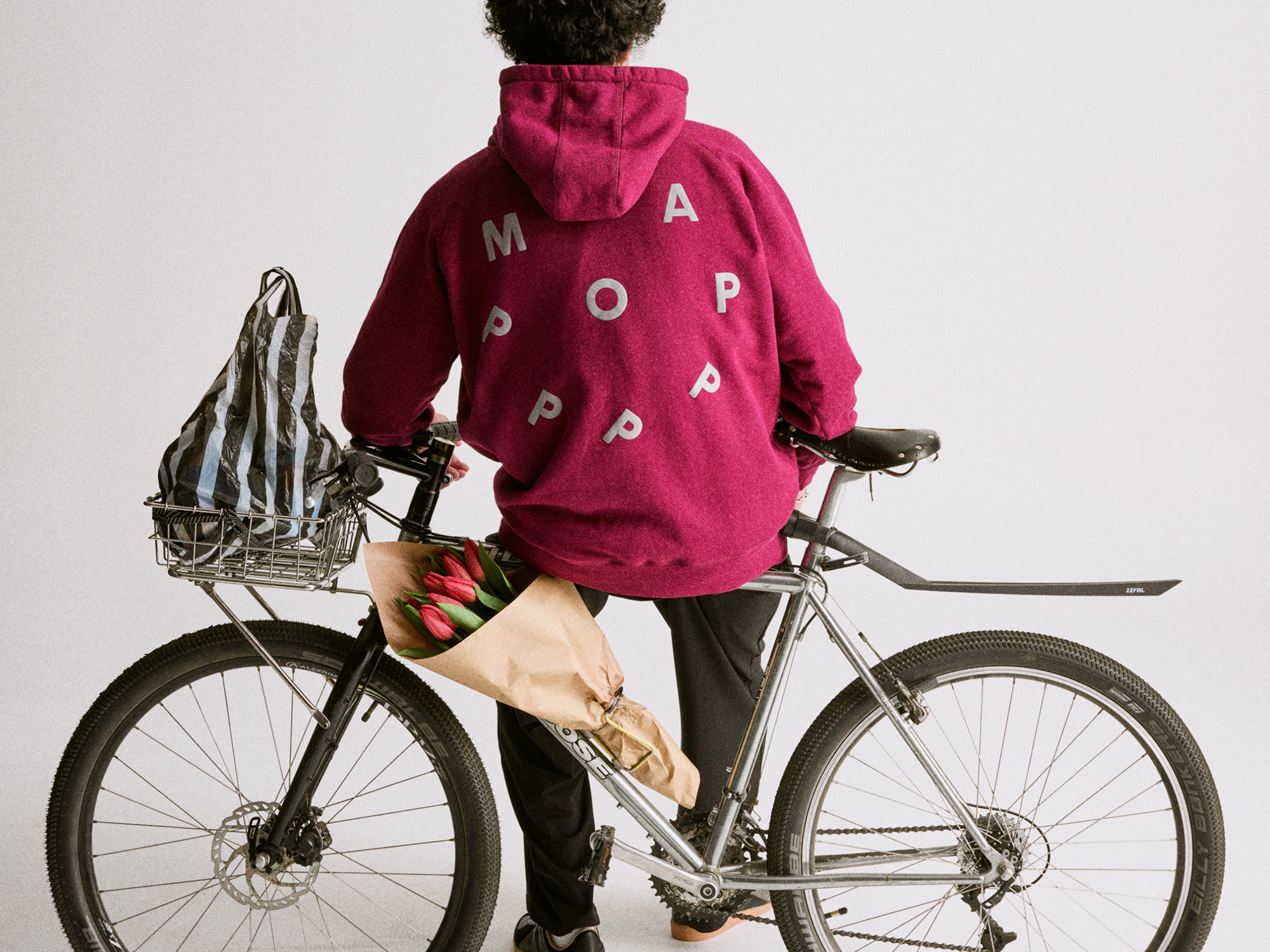 Man on bike wearing Maap Pop collab hoody 