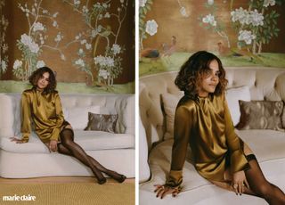 Halle Berry in a marigold colored dress and black tights sitting on a white couch