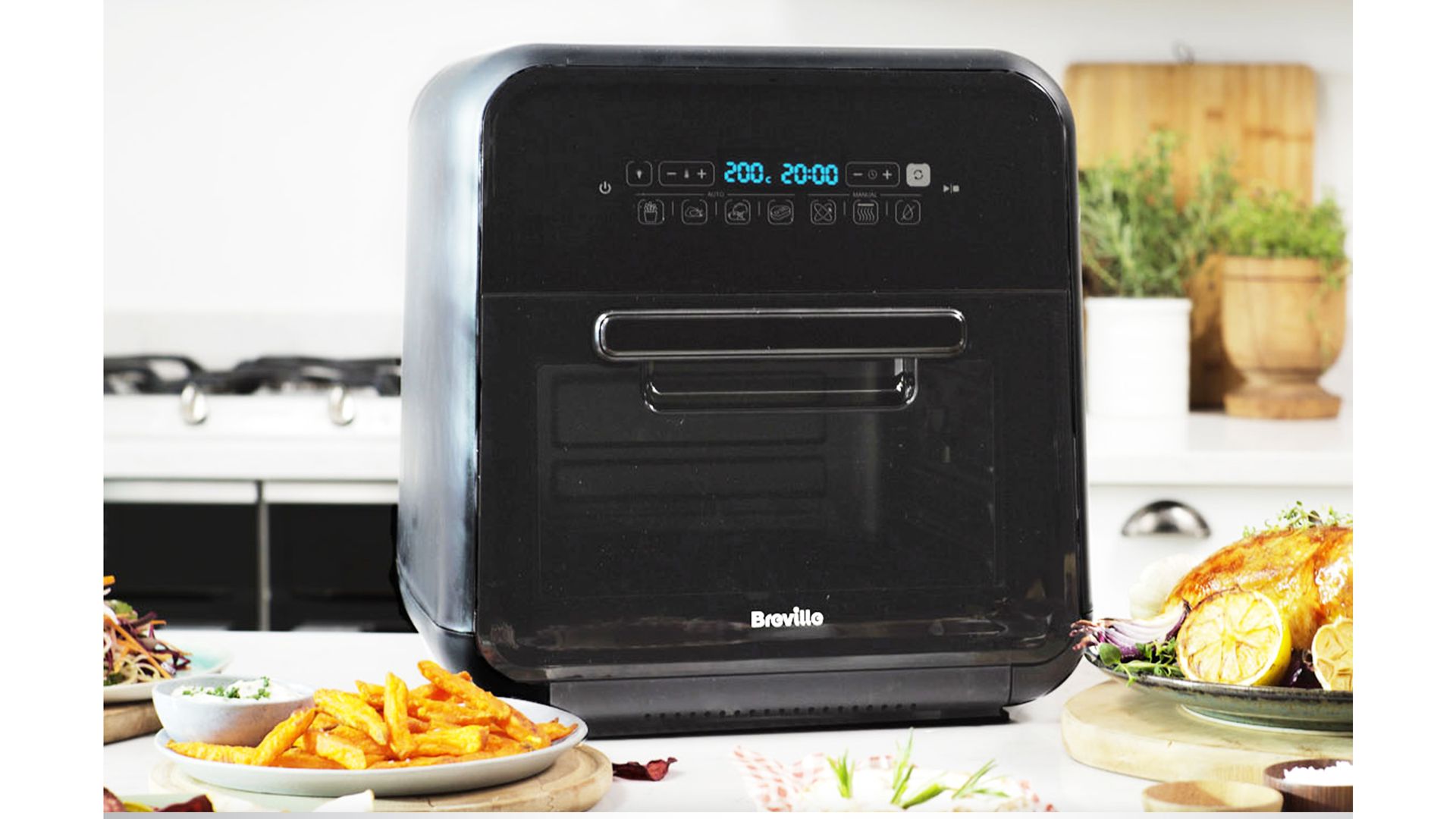 black air fryer oven on kitchen worktop with plate of chips prepared on the side