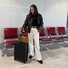Influencer wearing a black leather bomber jacket and cream jeans at the airport