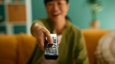 Woman pointing remote control out of the screen