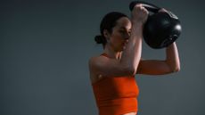 Woman doing beginner kettlebell workout, holding kettlebell and wearing activewear