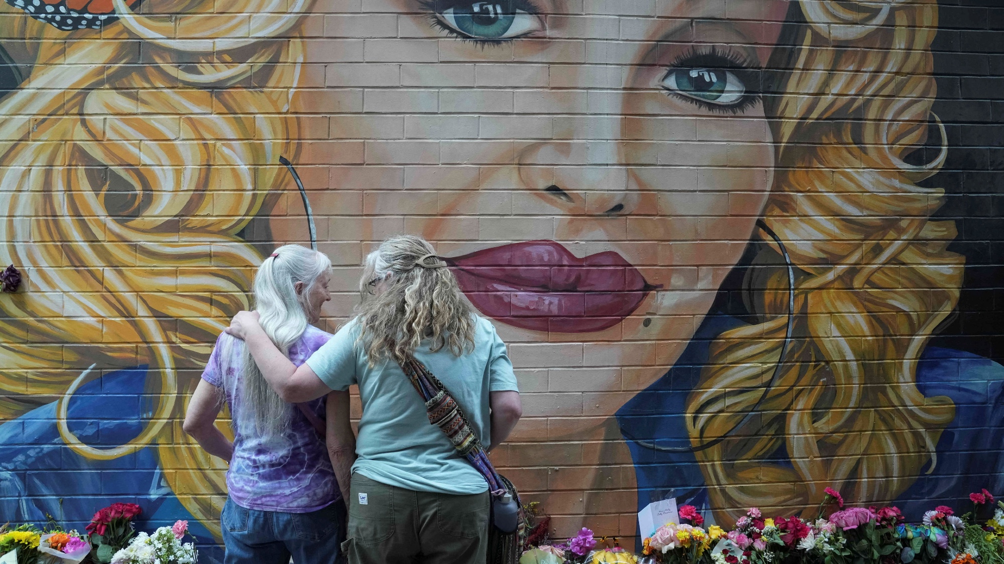 People gather by a mural to pay their respects to late country singer Dolly Parton in Knoxville, Tennessee