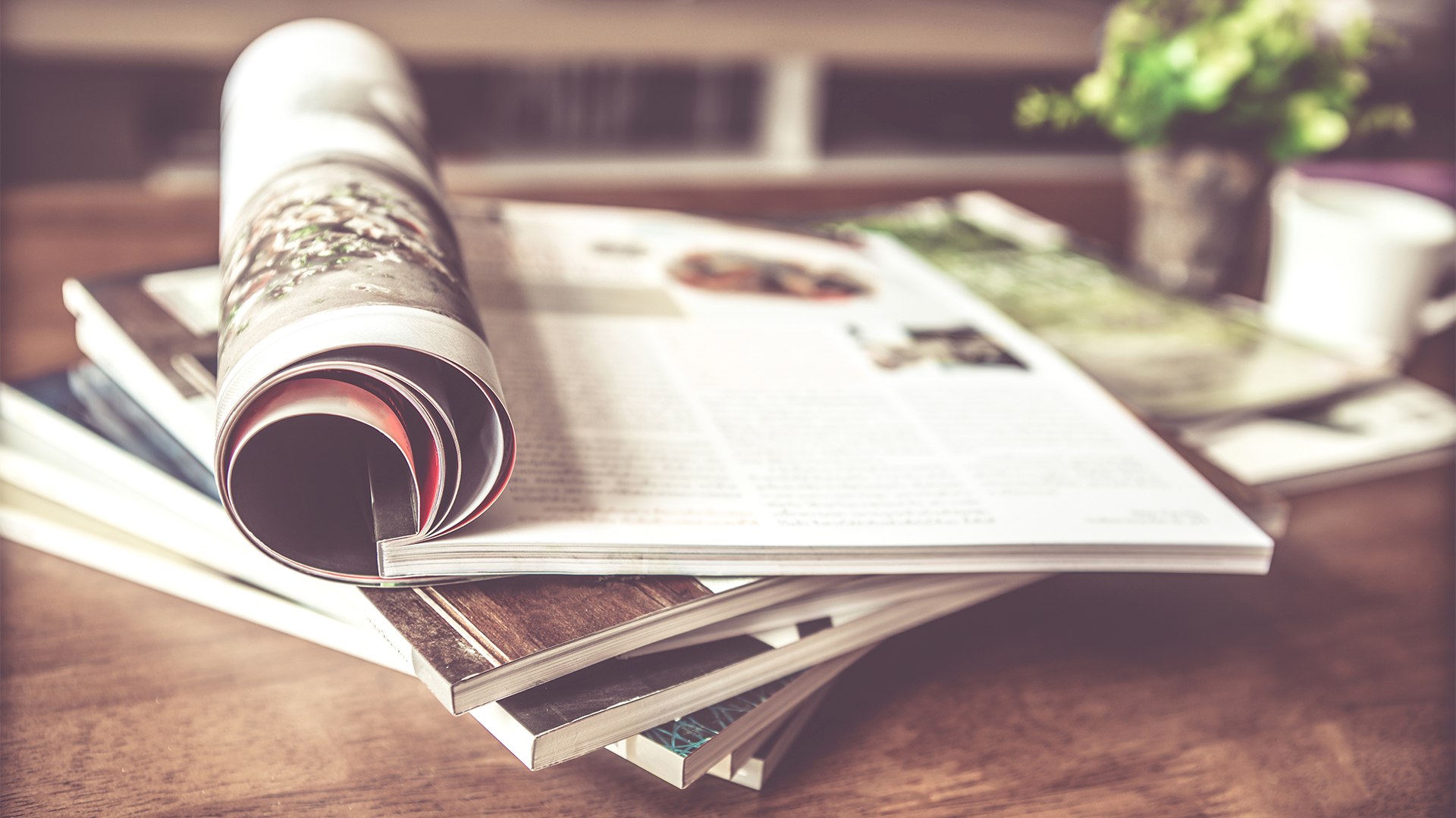 Old magazine rolled up placed on top of pile on a coffee table.