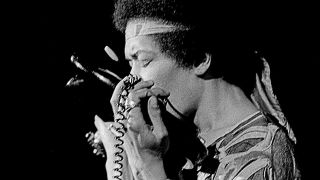 Jimi Hendrix playing guitar with his teeth