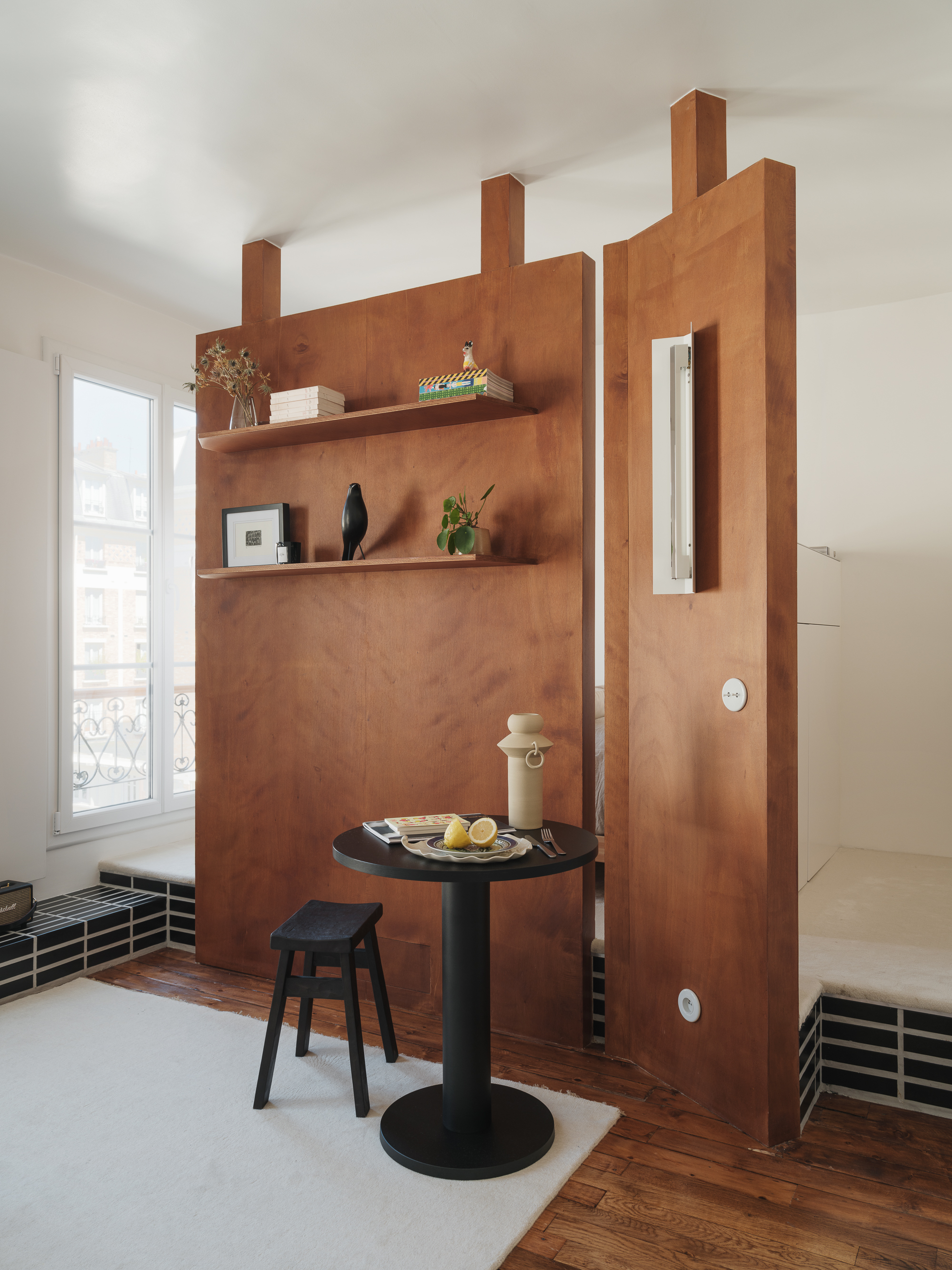 a wooden room divider in a small apartment between a dining space and bedroom