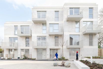 seen from the distance, among brick housing, the white volume of citizens house by archio in south london