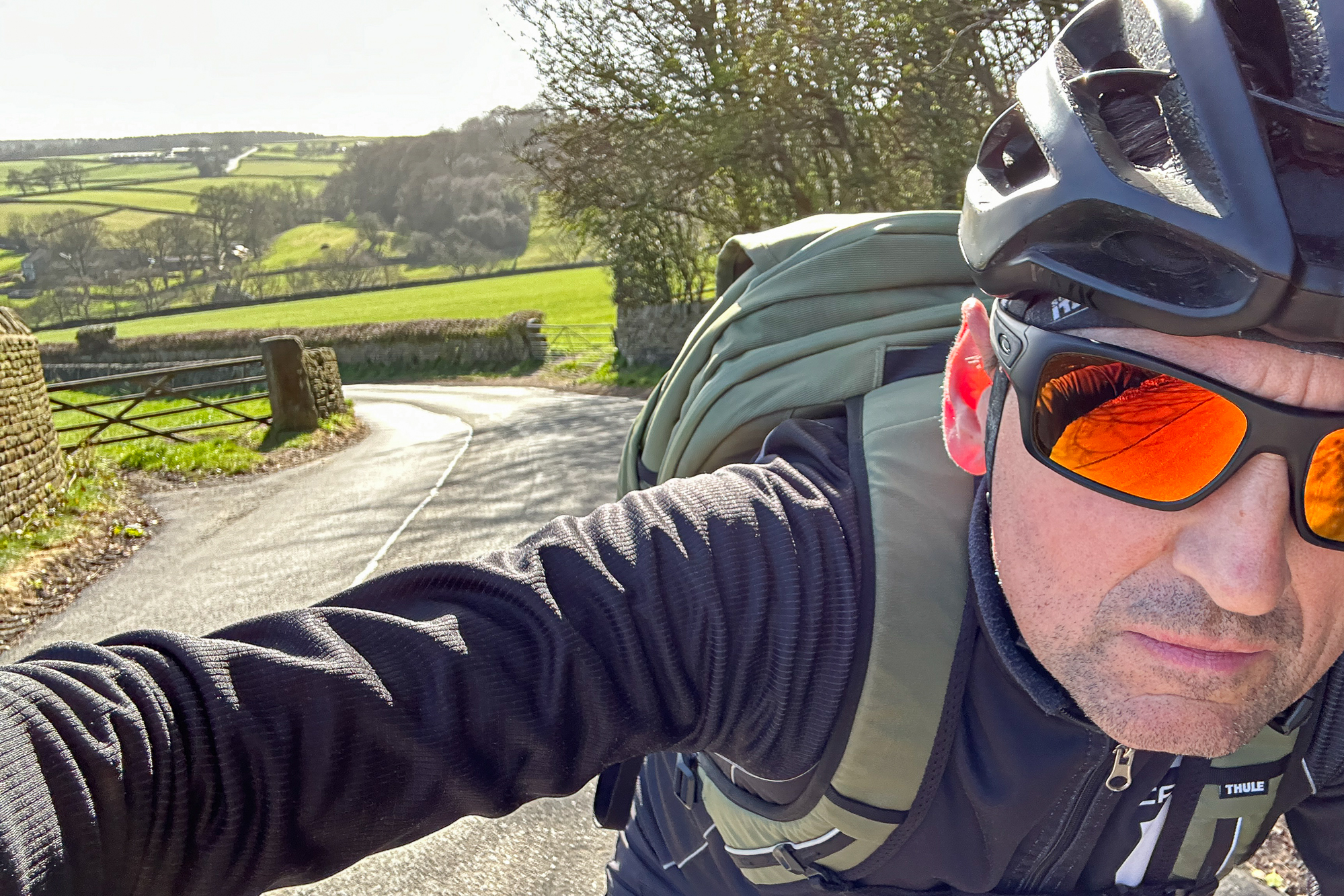 selfie of a man riding a bike with a black helmet and green rucksak