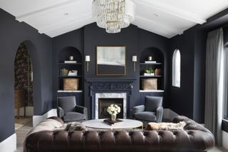 Living room with leather couch, dark walls and white vaulted ceiling
