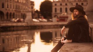 Jay Buchanan sitting by a canal, dangling his foot in the water