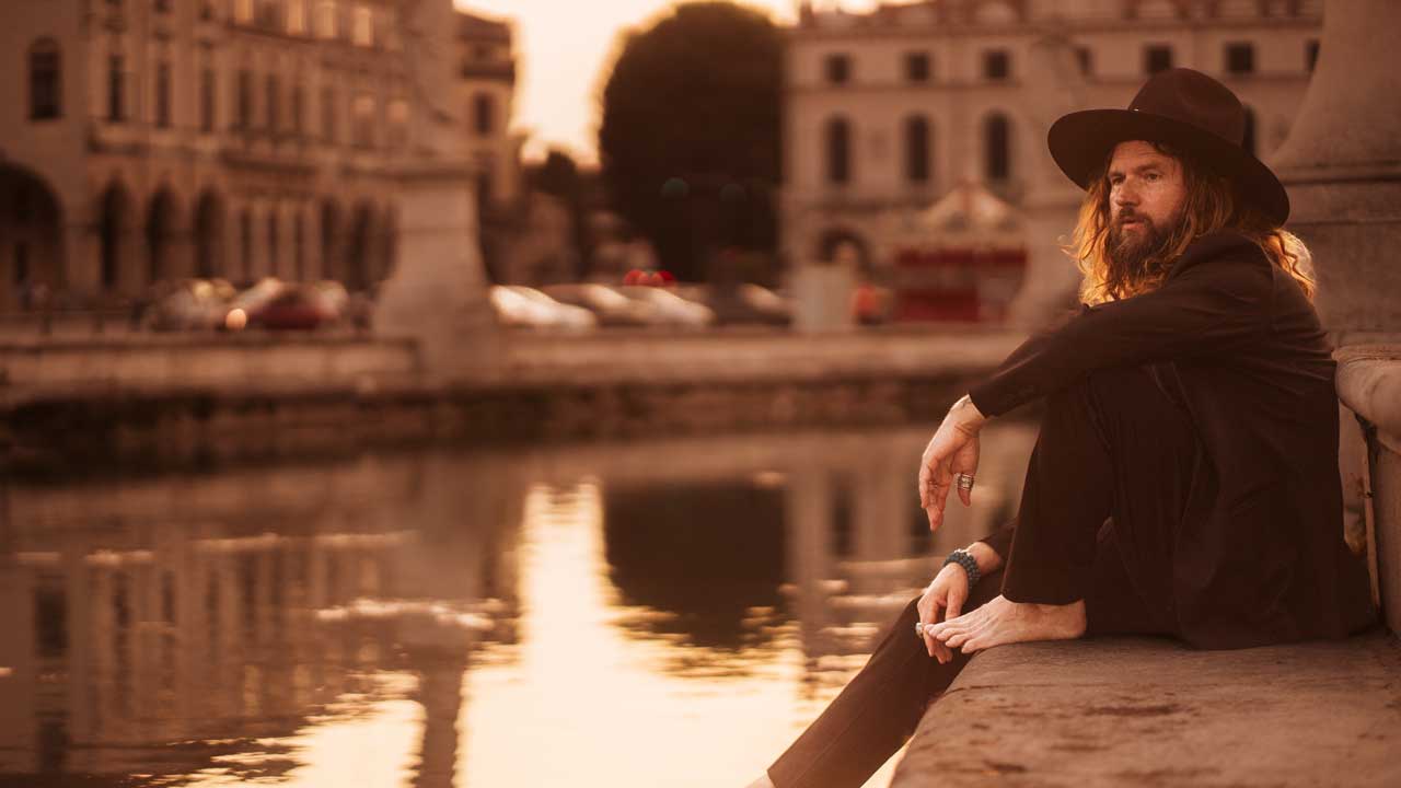 Jay Buchanan sitting by a canal, dangling his foot in the water