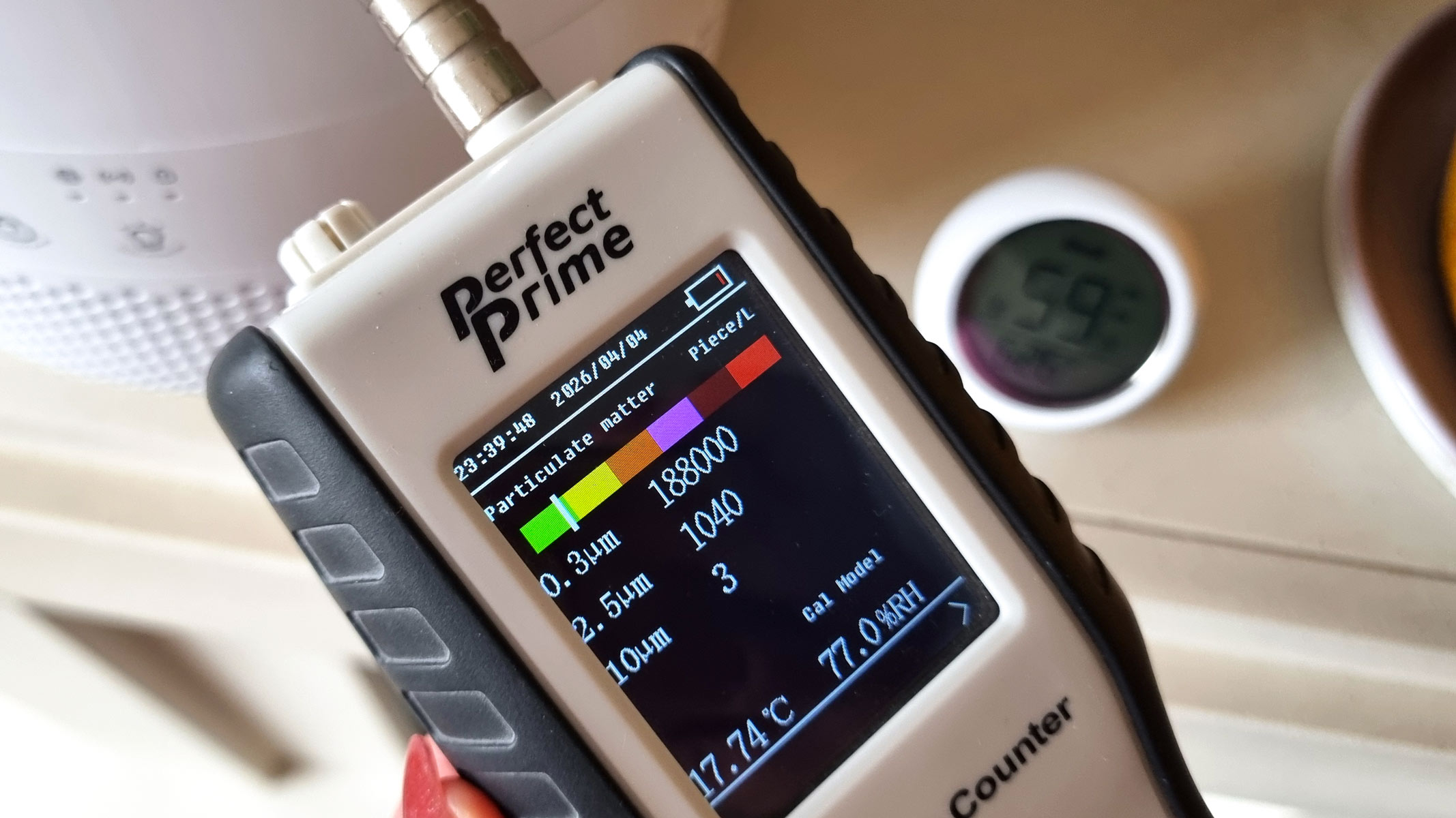a close-up picture of our reviewer testing the Levoit Sprout Evaporative Humidifier using the Perfect Prime air particle monitor and provided humidity meter