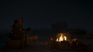 Bo-Katan eats by the campfire in The Mandalorian season 3 episode 4.