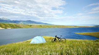 Tent and bike in field beside lake
