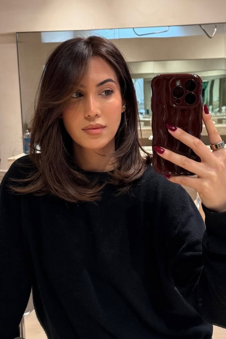 A model with their hair cut in long layers.