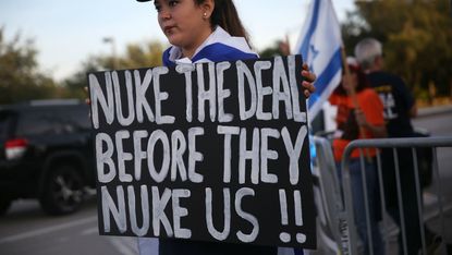 A demonstrator holds a sign calling for the US to "nuke" Iran before it can take nuclear action against the US.
