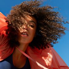 young female athlete with natural hair against clear blue sky