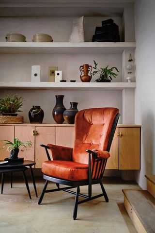 living room with cabinet, shelves and orange ercol armchair