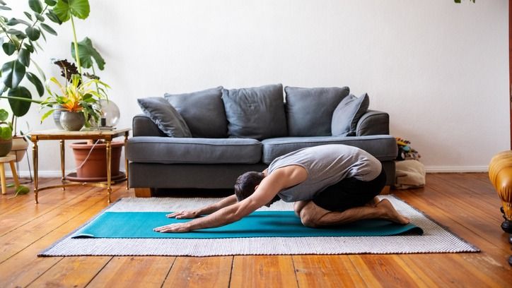 Man doing child&#039;s pose in his living room