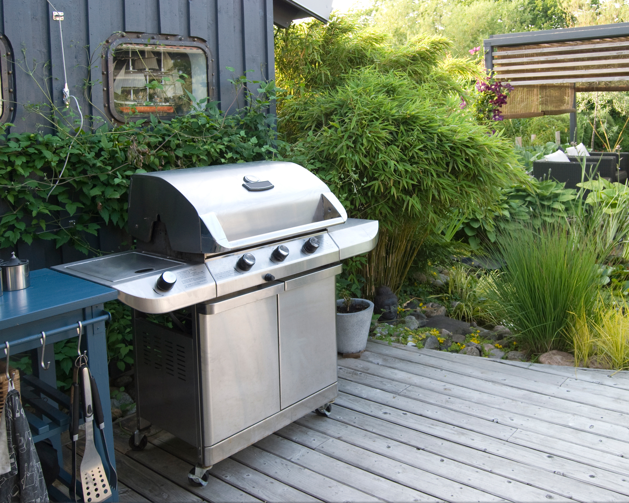 Outdoor kitchen with a stainless-steel gas grill and bamboo garden screening