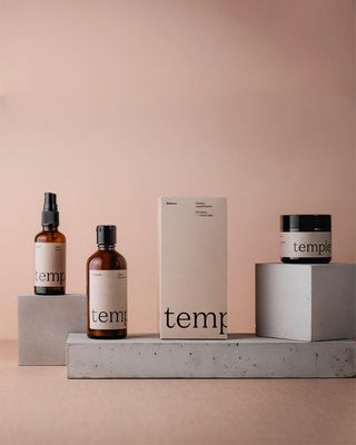 Temple vegan skincare products displayed on concrete blocks against blush background